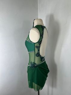 a woman's green and white dress with beading on the bust, sitting on a mannequin