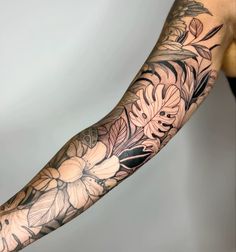 a woman's arm with flowers and leaves on it