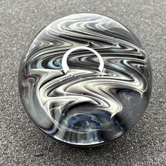 Handmade Contemporary Glass Art Marble. This marble is approximately 1.40" in diameter. This marble features a fumed wigwag wavy swirl design in the core of the marble that shows hues of mainly silver, grey, blue, etc. The marble has a clear lens and a decorated back. The backing is decorated with a green pinwheel design.  This item was handmade in a glassblowing studio using Lampworking and flame working techniques. Made by USA Based Glass Artist Eric Spinney.  Made of Borosilicate Glass. This Item is brand new. Ships via USPS. Please note the item is handmade and a unique 1/1 item. Colors and hues may vary slightly due to different lighting conditions. Colors may appears differently on different devices screens. Please note that the intensity of fumed glass often varies depending on ligh Pinwheel Design, Glassblowing Studio, Contemporary Glass Art, Contemporary Glass, Glass Marbles, Swirl Design, Grey Blue, Glass Artists, Dark Backgrounds