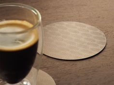 a close up of a drink in a glass on a table with a paper coaster