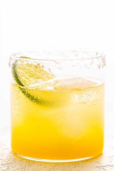 a close up of a drink in a glass with a lime slice on the rim