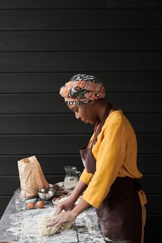 a woman in an apron is kneading dough on a table with other ingredients