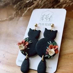 the black cat earrings are decorated with flowers