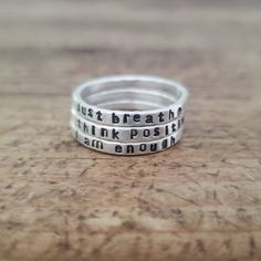 "This personalized hammered ring is hand stamped with the quote or word of your choice. I form these rings from thick sterling silver wire and then hammer them to size. It leaves them with a subtle hammered finish. I then hand stamp the quote onto the rings. They are skinny yet thicker than some of my other name rings. These rings are available in sterling silver or 14K gold and are approximately 2mm wide. In the photos, the rings have a matte finish, but they can also have a shiny or brushed fi Inspirational Personalized Sterling Silver Rings, Inspirational Hand Stamped Silver Rings, Inspirational Adjustable Sterling Silver Rings, Adjustable Inspirational Sterling Silver Rings, Meaningful Adjustable Silver Stackable Rings, Inspirational Adjustable Hand Stamped Rings, Meaningful Silver Stackable Rings, Silver Hand-stamped Engraved Ring, Meaningful Engraved Silver Stackable Rings