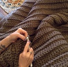 the woman is knitting her sweater on the couch