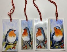 three tags with birds painted on them hang from red string and are decorated with berries