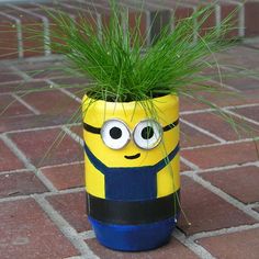 a yellow and blue minion planter with grass in it