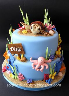 a blue cake decorated with an octopus and sea life on the bottom layer, along with a sign that says diego