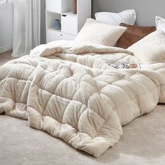 an unmade bed with white pillows and blankets on top of it in a bedroom