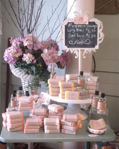 a table topped with lots of soaps next to a vase filled with pink flowers