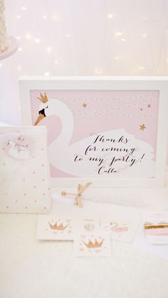 a pink swan themed baby's first birthday party with personalized cards and decorations