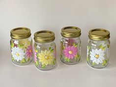 four glass jars with painted flowers on them