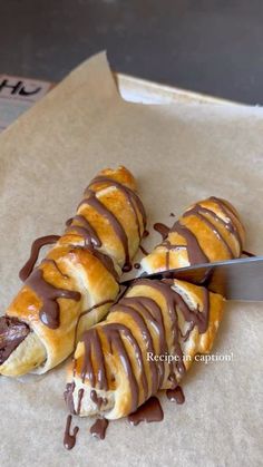 a pastry with chocolate drizzled on it being cut by a large knife