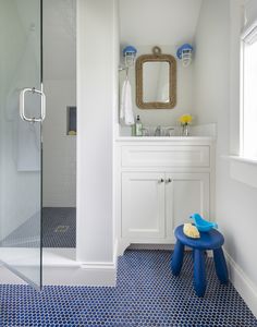 a blue and white bathroom with a stool in the middle of the room, along with a shower stall