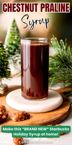 a glass filled with chocolate syrup sitting on top of a wooden cutting board next to christmas trees