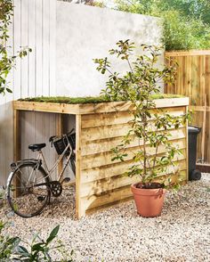 a bike is parked in front of a wooden structure with plants growing out of it