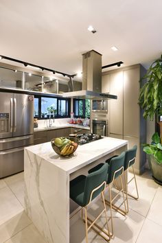 a modern kitchen with stainless steel appliances and marble counter tops, along with green chairs