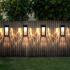 the light is shining through three windows on a wooden fence with grass and trees in the background