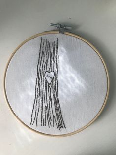 a white embroidery with black thread and a heart on it