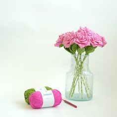 pink flowers in a vase with yarn next to it