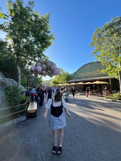 a woman walking down a street next to trees