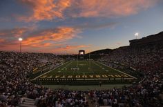 a football stadium filled with lots of people watching the sun go down on it's field