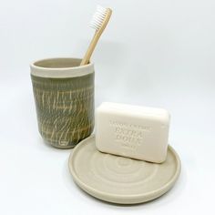 a cup with a toothbrush in it next to a soap bar