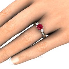 a woman's hand with a ring on it and a red stone in the middle