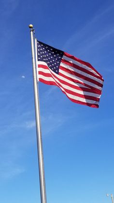 an american flag flying in the wind on a clear day with blue sky and white clouds