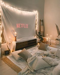 an unmade bed with candles and lights on the headboard in front of it