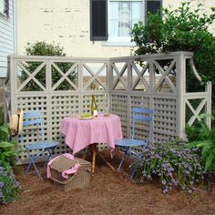 a table and chairs sitting in the middle of a yard with flowers growing around it