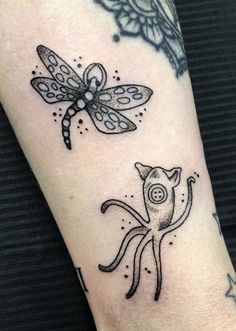 an arm with some tattoos on it and a dragon in the middle, sitting next to a cat