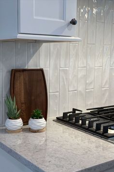 a kitchen counter with a potted plant on it and a wooden cutting board in front of the stove