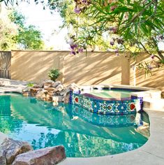 an outdoor pool with rocks and plants around it