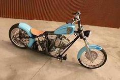 a blue and black motorcycle parked on top of a cement floor next to a wall