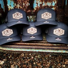 five hats sitting on top of a rusted metal rail in front of a rusty wall