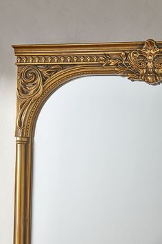 an ornate gold framed mirror against a white wall