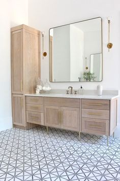 a bathroom with a large mirror above the sink and two wooden cabinets in front of it