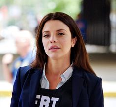 a woman wearing a t - shirt with the words bt on it is standing in front of a building