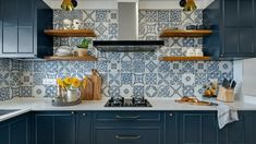 a kitchen with blue cabinets and white counter tops is pictured in this image, there are wooden shelves above the stove