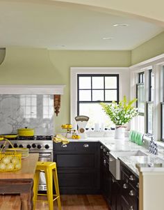 a kitchen with black cabinets and yellow stools