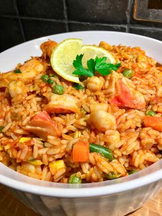 a white bowl filled with rice and veggies next to a slice of lime