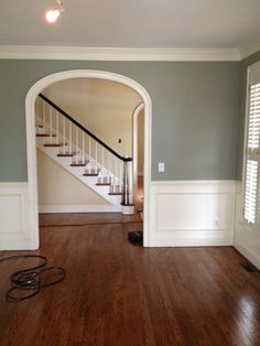 an empty living room with hard wood flooring and white trim on the walls, along with a stair case