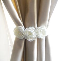 three white roses are attached to the curtain