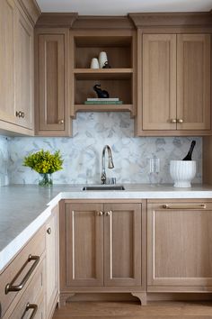 a kitchen with wooden cabinets and white marble counter tops, along with a vase filled with flowers