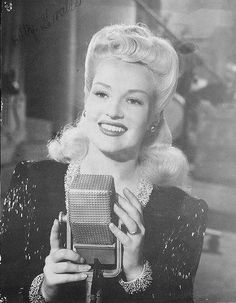 an old black and white photo of a woman holding a microphone in front of her face