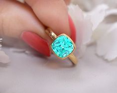 a woman's hand holding a gold ring with blue topaz