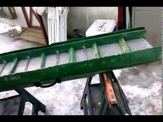 there is a green machine that has been placed on top of some snow covered ground