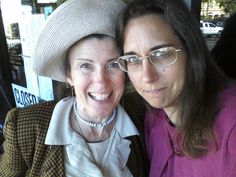 two women are posing for the camera with one woman wearing glasses and a hat on her head