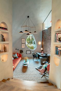 a living room filled with furniture and a circular window in the wall next to bookshelves